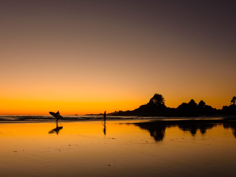 Ein Surfer während des Sonnenuntergangs an einem Strand auf Van